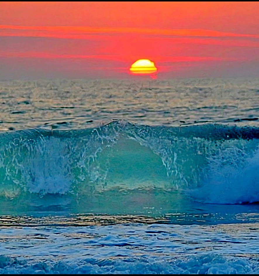 Sunrise over the ocean with a breaking turquoise wave